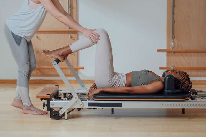 Woman performing pilates with a pilates tranier.