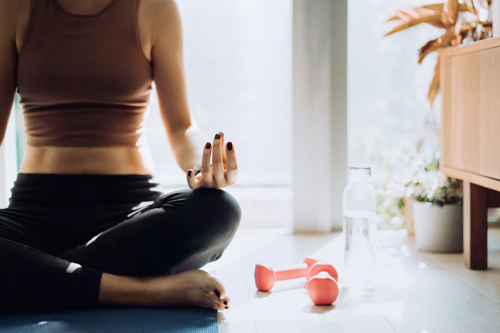 Woman sitting on the floor with a green smoothie in her hand.